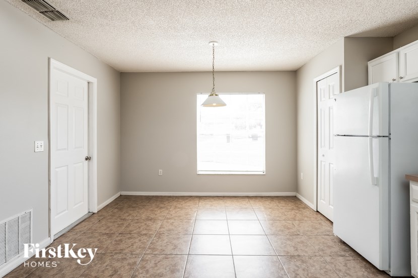 A kitchen with a white refrigerator and a tiled floor.