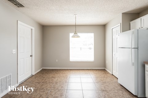 A kitchen with a white refrigerator and a tiled floor.