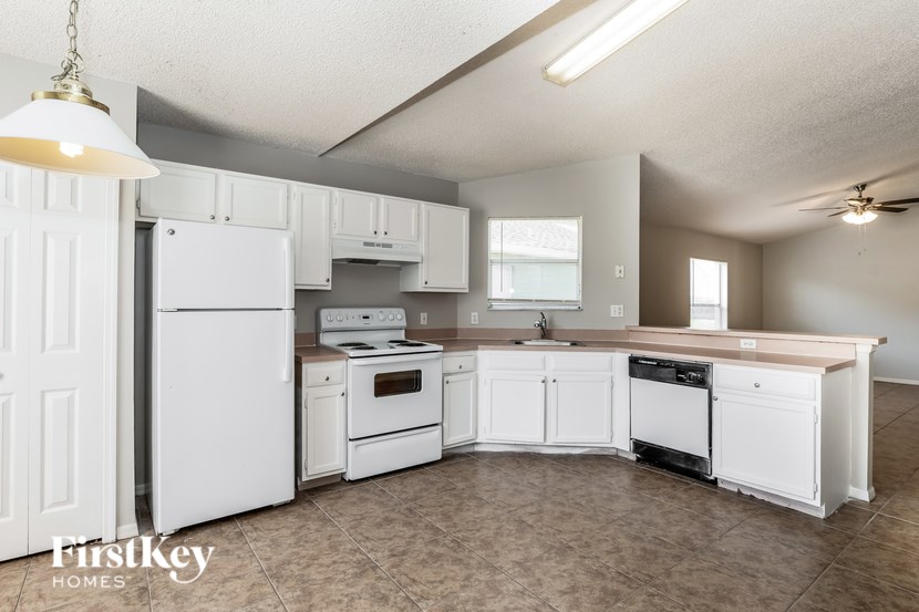 A kitchen with white appliances and cabinets.