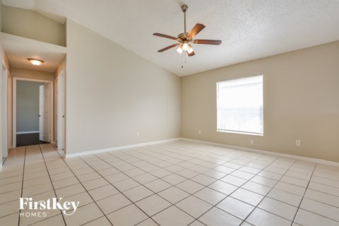 an empty living room with a ceiling fan and tiled floors