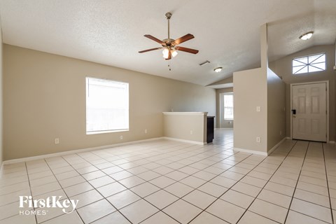 an empty living room with a ceiling fan