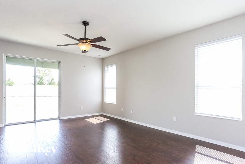 A room with a ceiling fan and sliding glass doors.