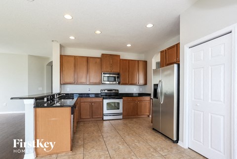 A kitchen with wooden cabinets and a black counter top.