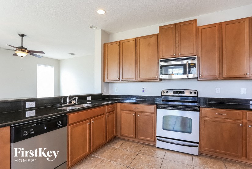 A kitchen with wooden cabinets and black countertops.