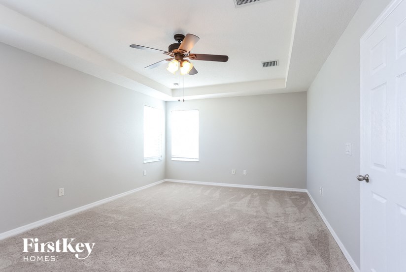 A spacious room with a ceiling fan and carpeted floor.
