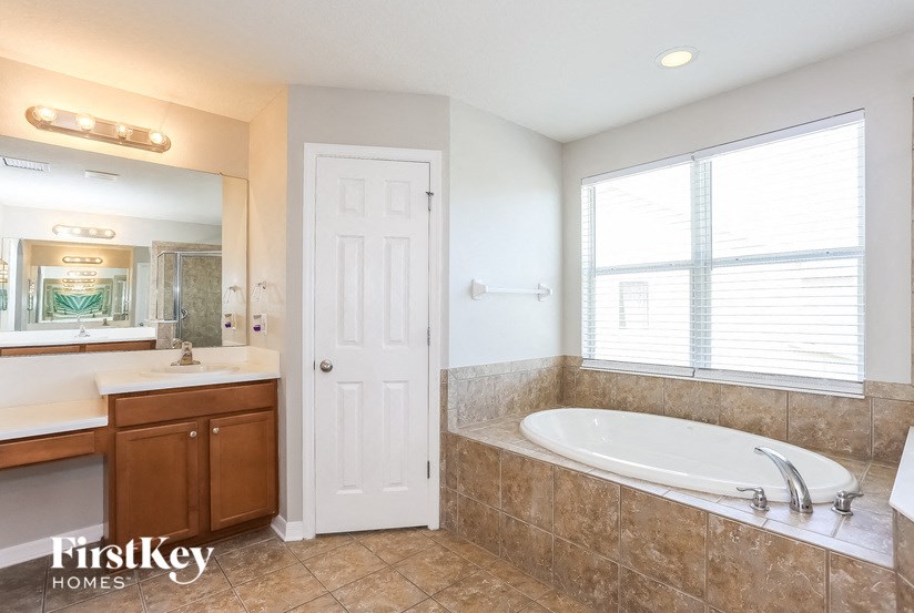 A bathroom with a tub, sink, and mirror.