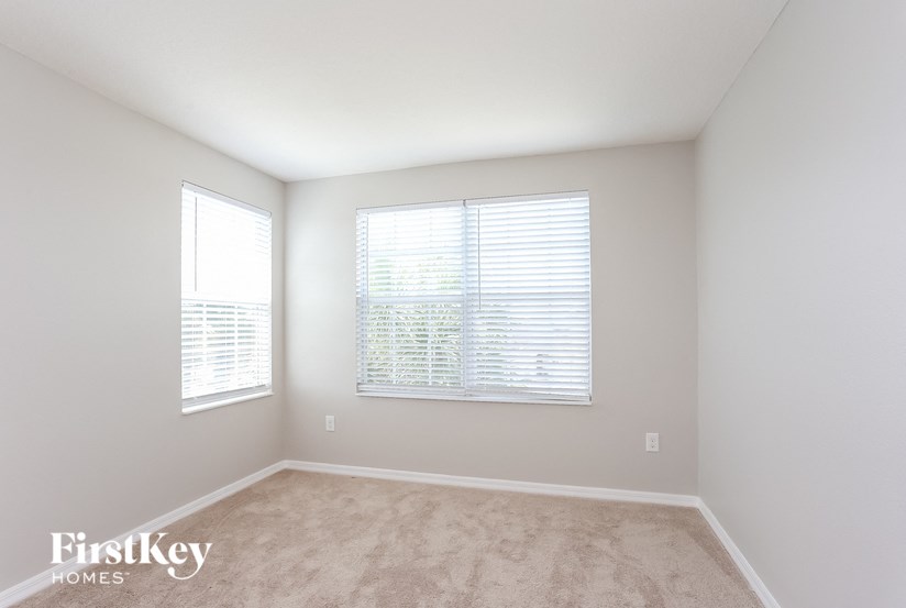 A room with a carpeted floor and two windows.