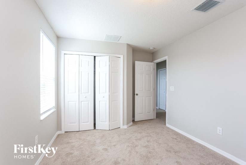 A room with white walls and a carpeted floor with a FirstKey Homes logo.