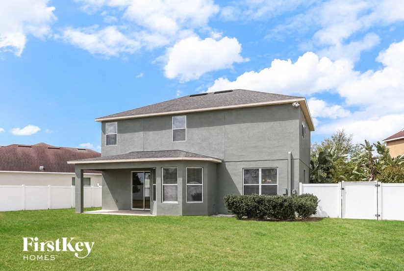 A grey house with a white fence in front of it.