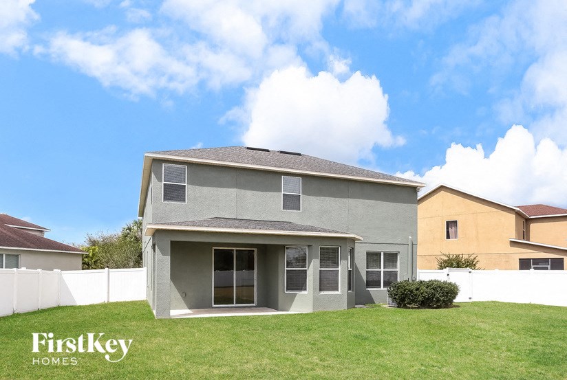 A grey house with a white fence in front of it.