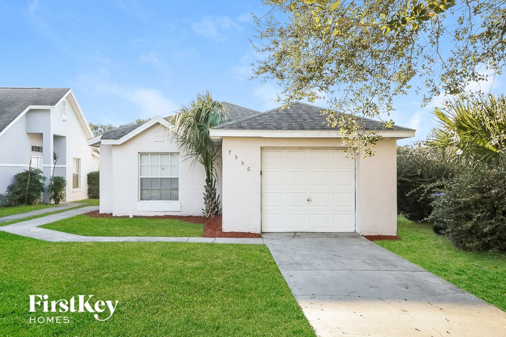 a white house with a white garage door and a lawn