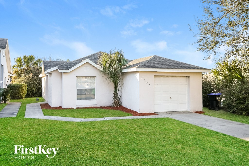 a small white house with a lawn and a garage