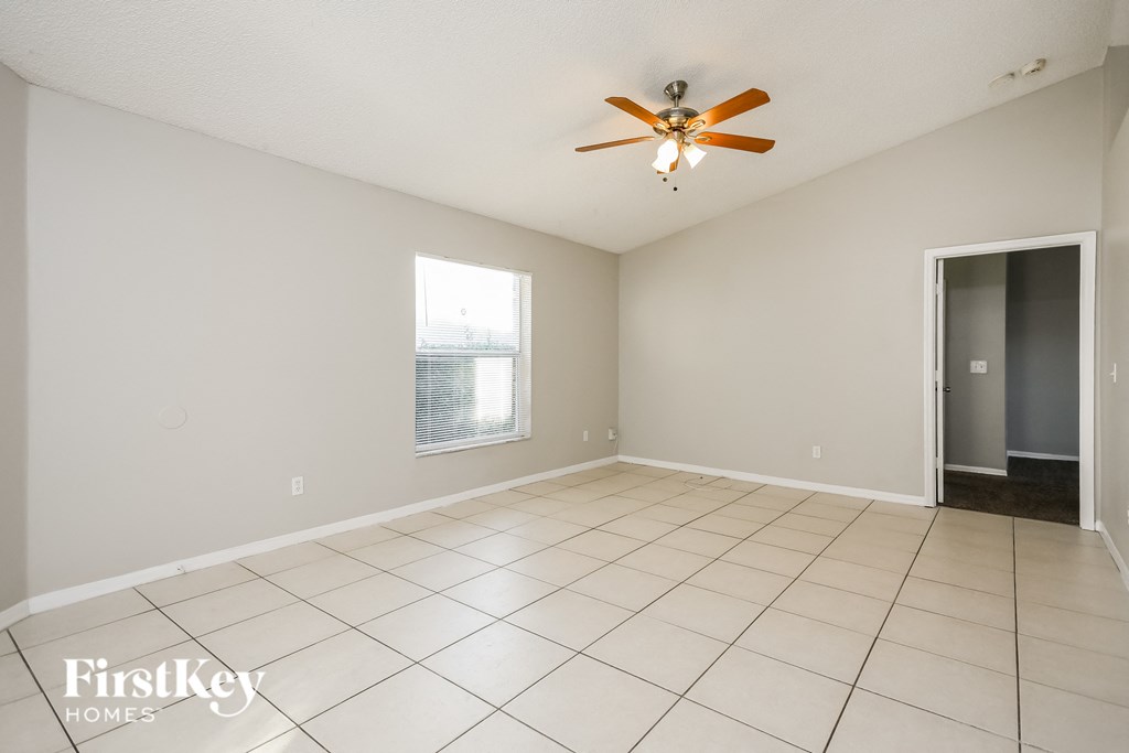 an empty living room with a ceiling fan and tiled floor