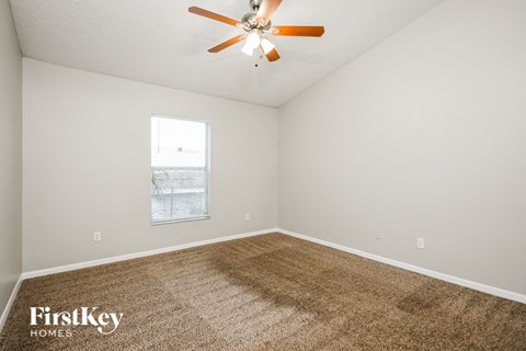 a spacious living room with carpet and a ceiling fan