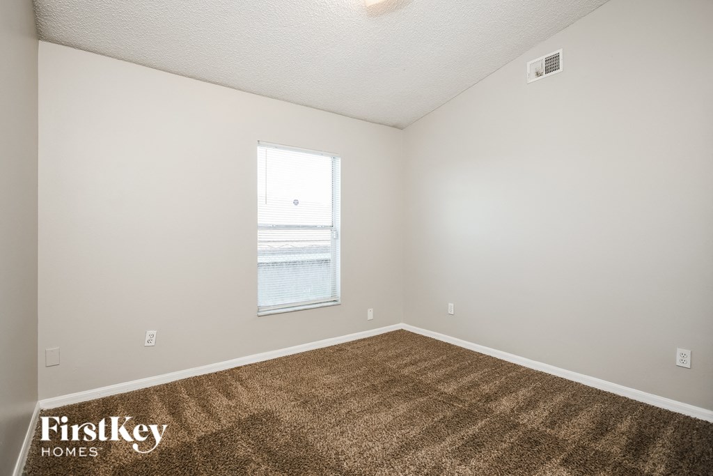 the living room of an apartment with carpet and a window