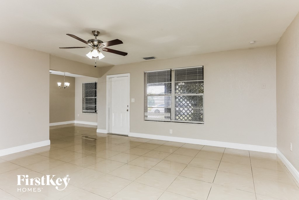 an empty living room with a ceiling fan and a window