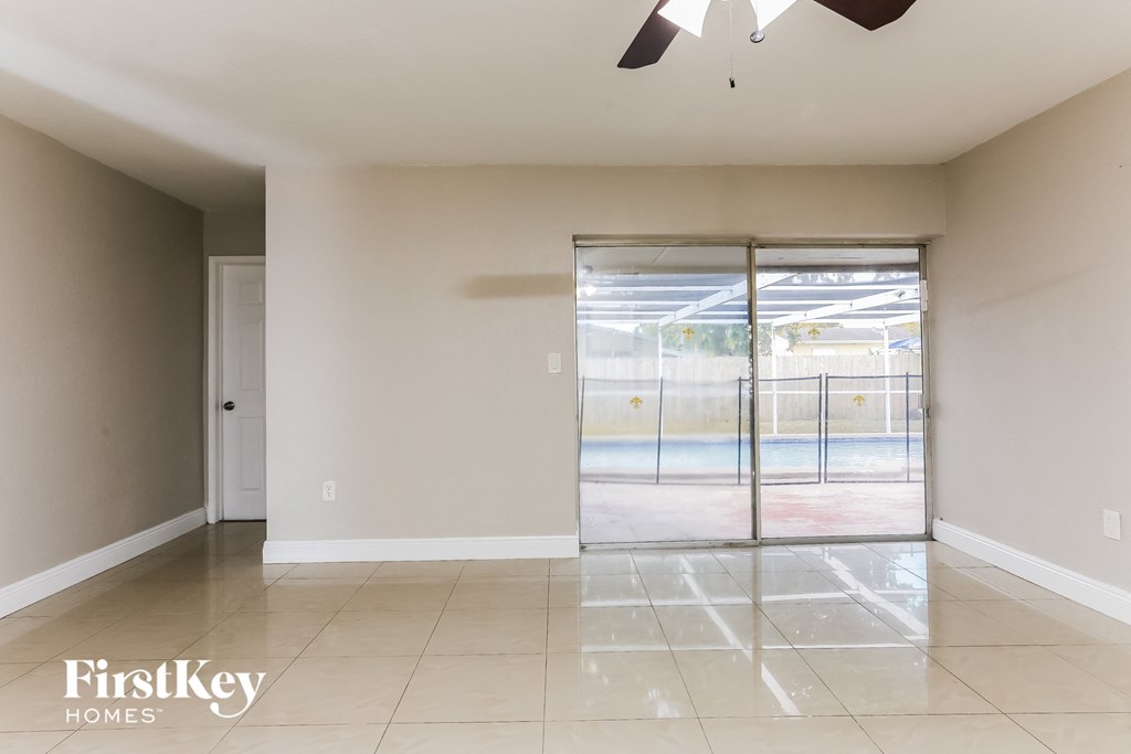 an empty living room with a sliding glass door to a pool