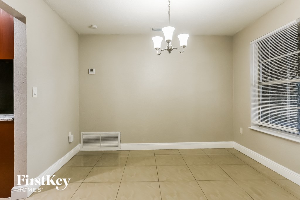 a empty dining room with a window and a chandelier