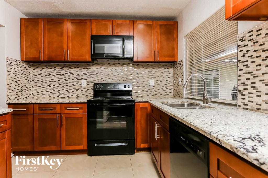 a kitchen with wood cabinets and black appliances and a counter top