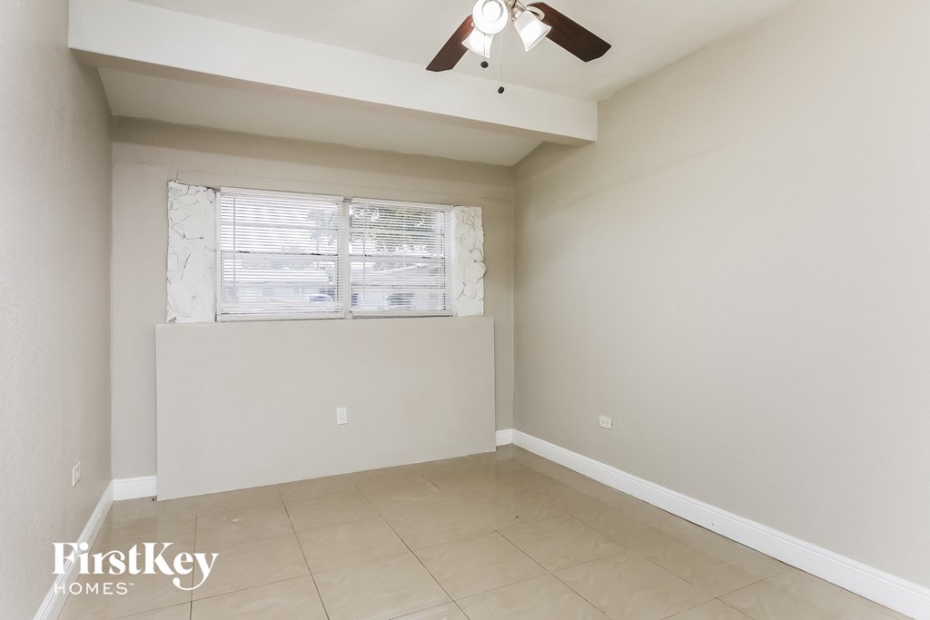 an empty room with a window and a ceiling fan