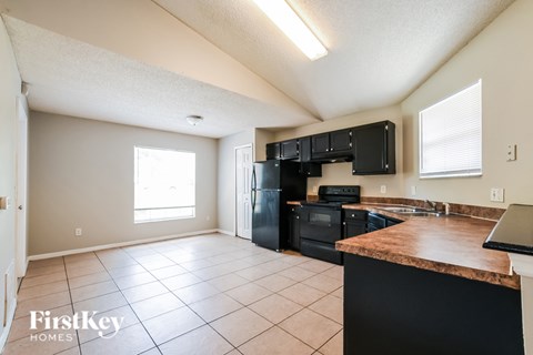 A kitchen with black appliances and a brown countertop.