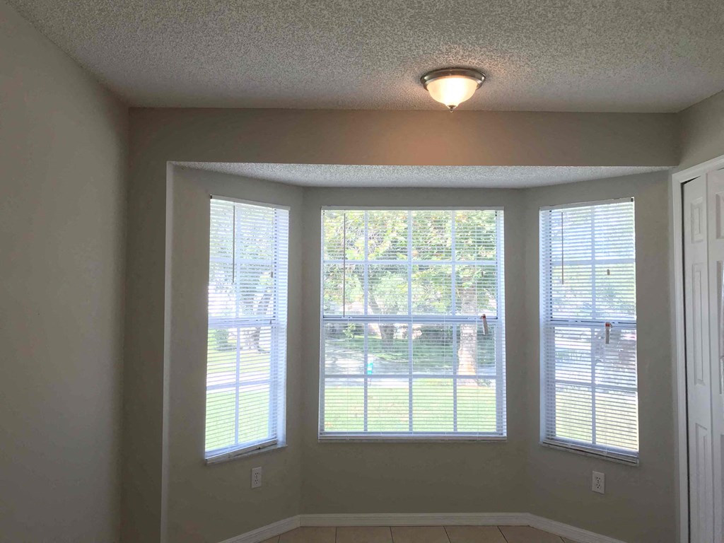 A room with a view of a yard through three windows.