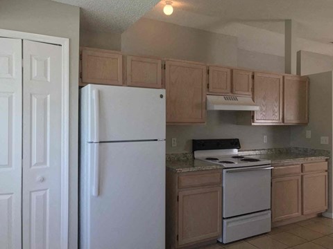 A white refrigerator stands in a kitchen with wooden cabinets.