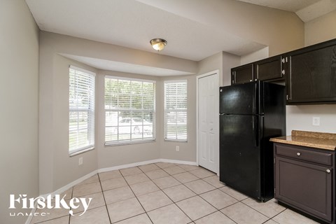 a kitchen with a large window and a black refrigerator