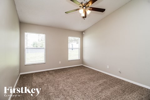 the master bedroom has carpet and a ceiling fan