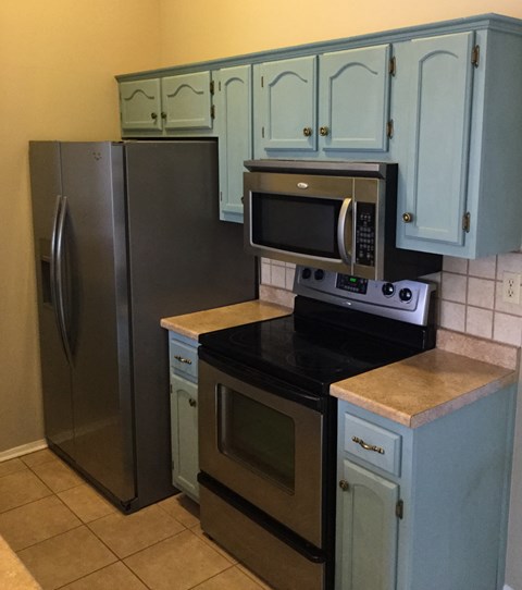 A kitchen with a black refrigerator, black stove, and black microwave.
