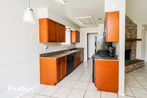 A kitchen with orange cabinets and a black stove top oven.
