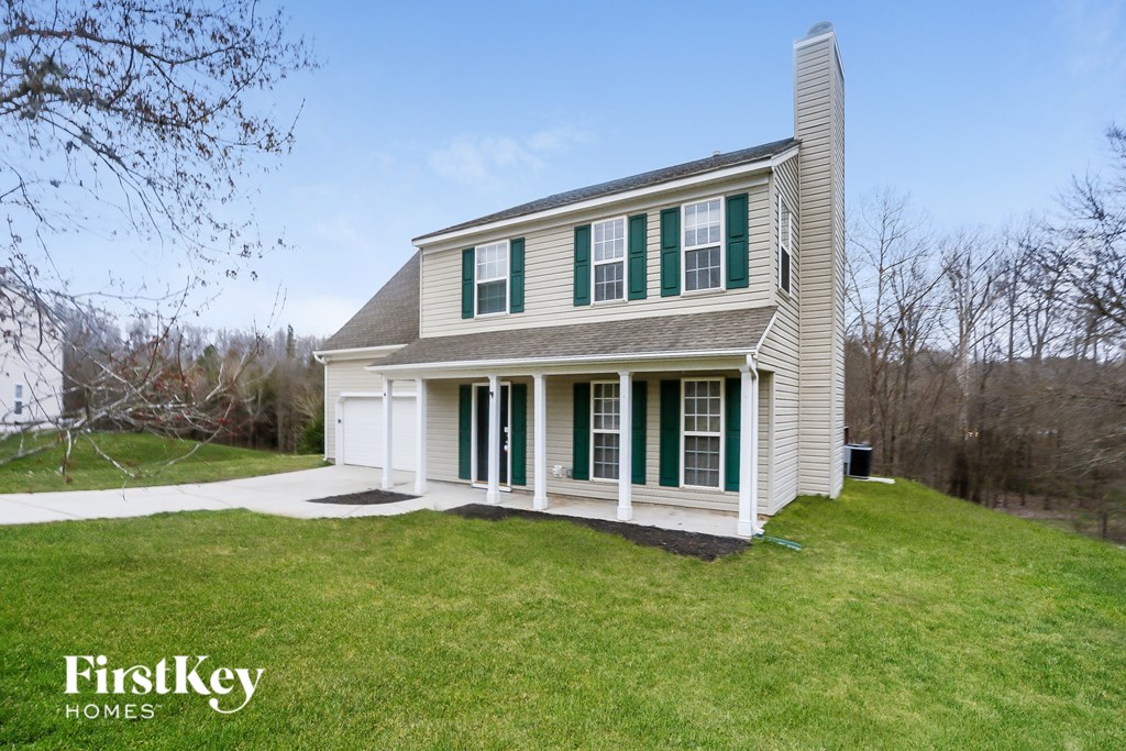 A house with a green lawn and a tree in the background.