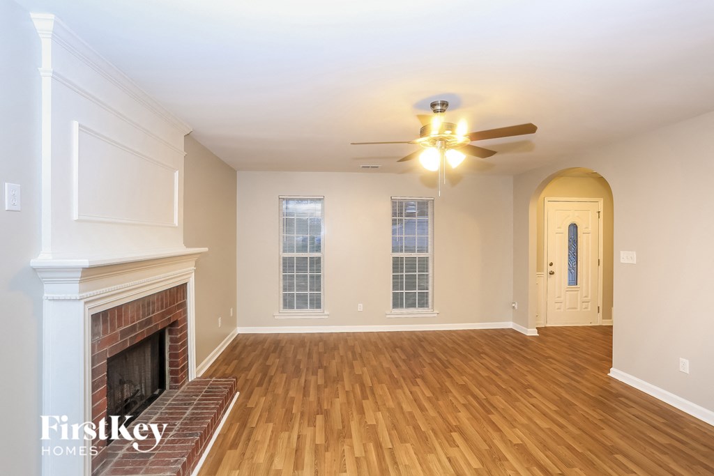 A spacious room with a fireplace and wooden floors.