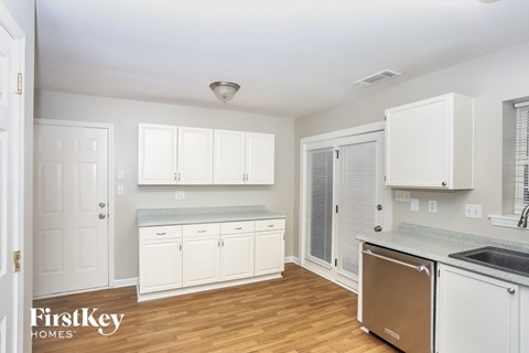 A kitchen with white cabinets and a wooden floor.