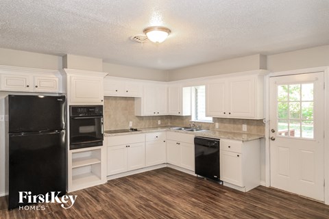 A kitchen with white cabinets and a black fridge.
