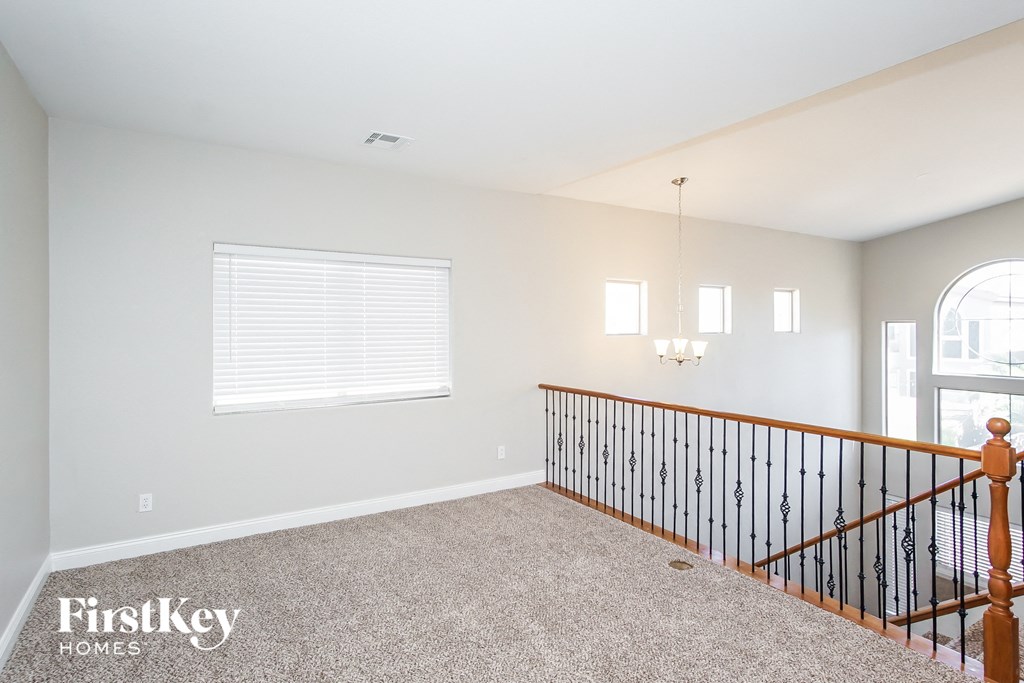 the upstairs loft has a large window and carpeted flooring