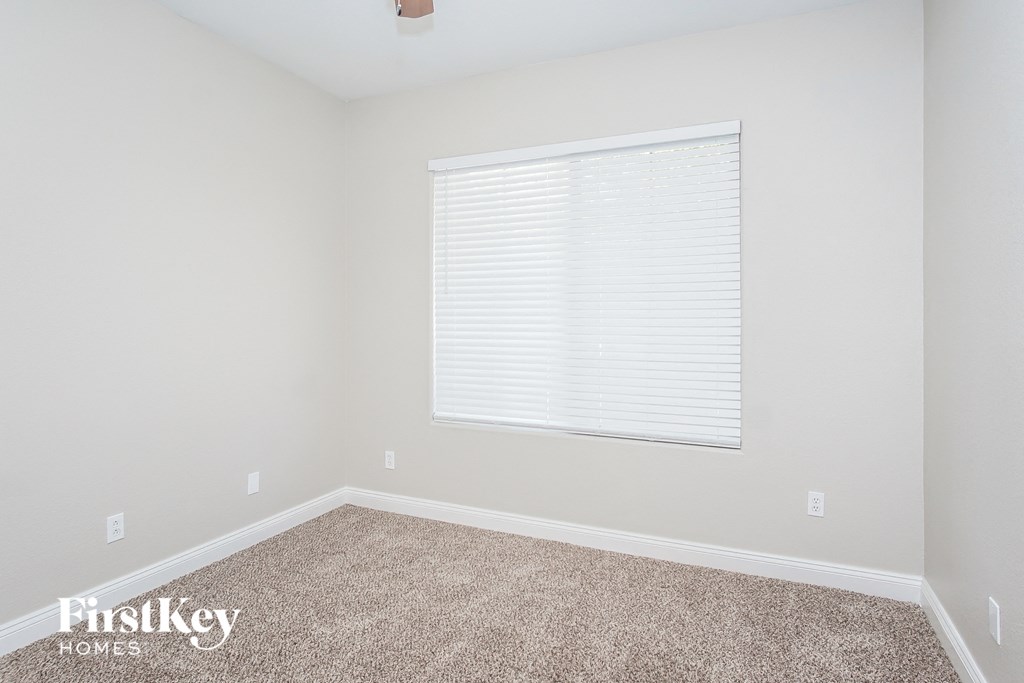 a bedroom with a window and a carpeted floor
