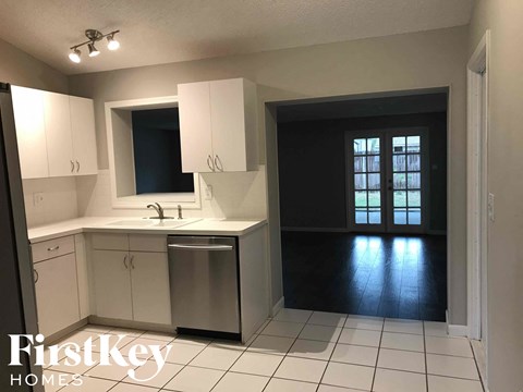 A kitchen with white cabinets and a black door.