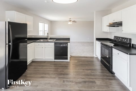 A kitchen with black appliances and white cabinets.