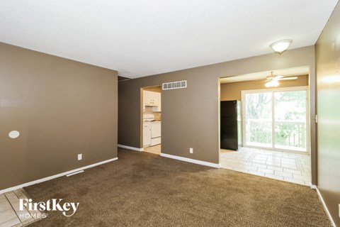 an empty living room with carpet and a door to the kitchen