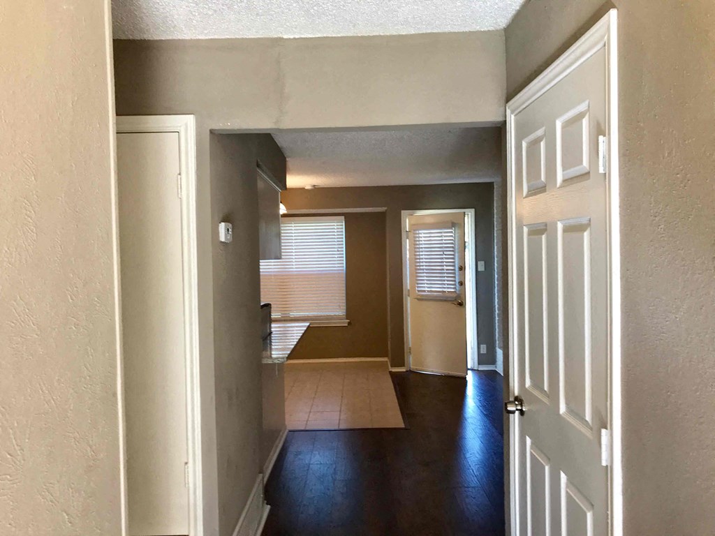 a view of a living room and a kitchen from the hallway