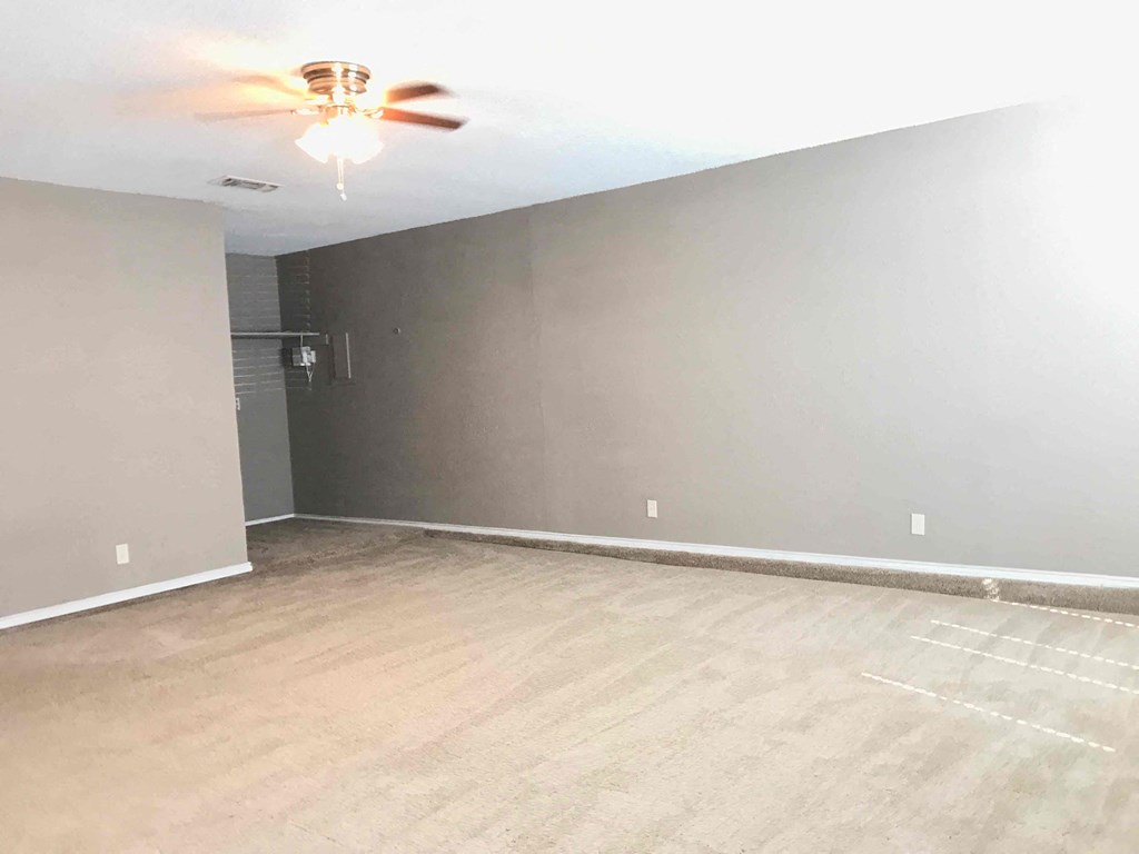 an empty living room with wood floors and a ceiling fan