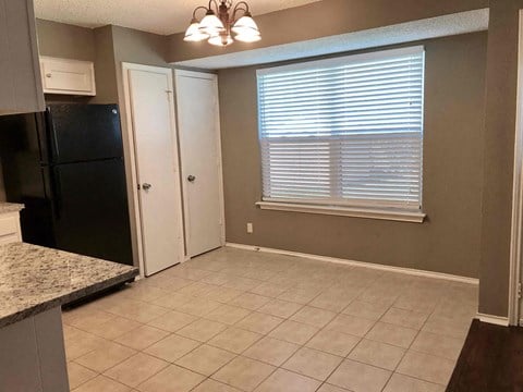 a kitchen with a black refrigerator and a window