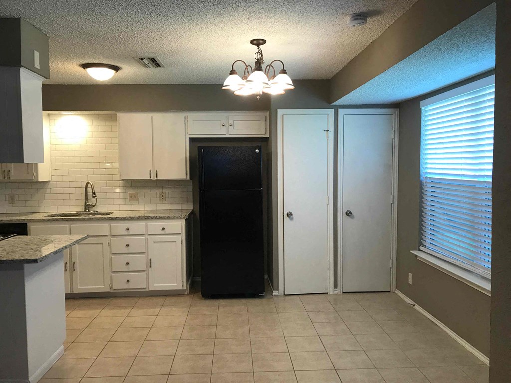a kitchen with white cabinets and a black refrigerator