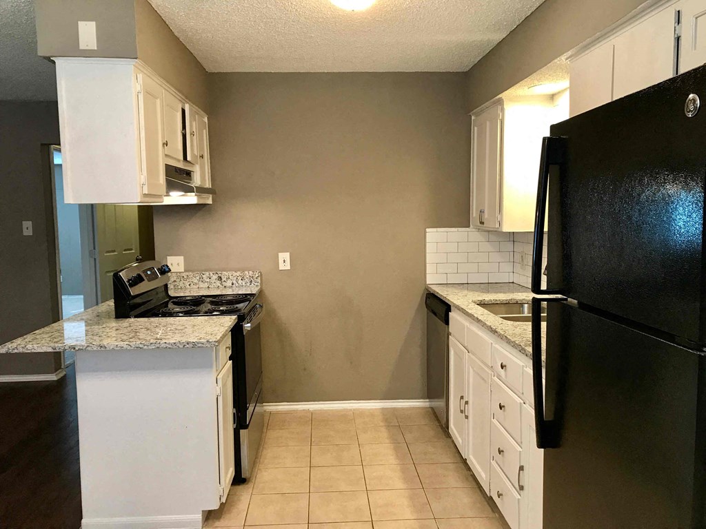 a kitchen with white cabinets and a black refrigerator