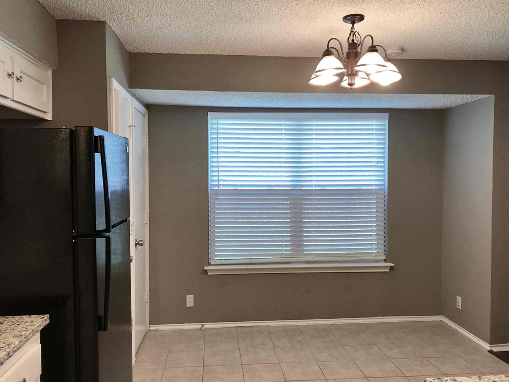 a kitchen with a large window and a black refrigerator