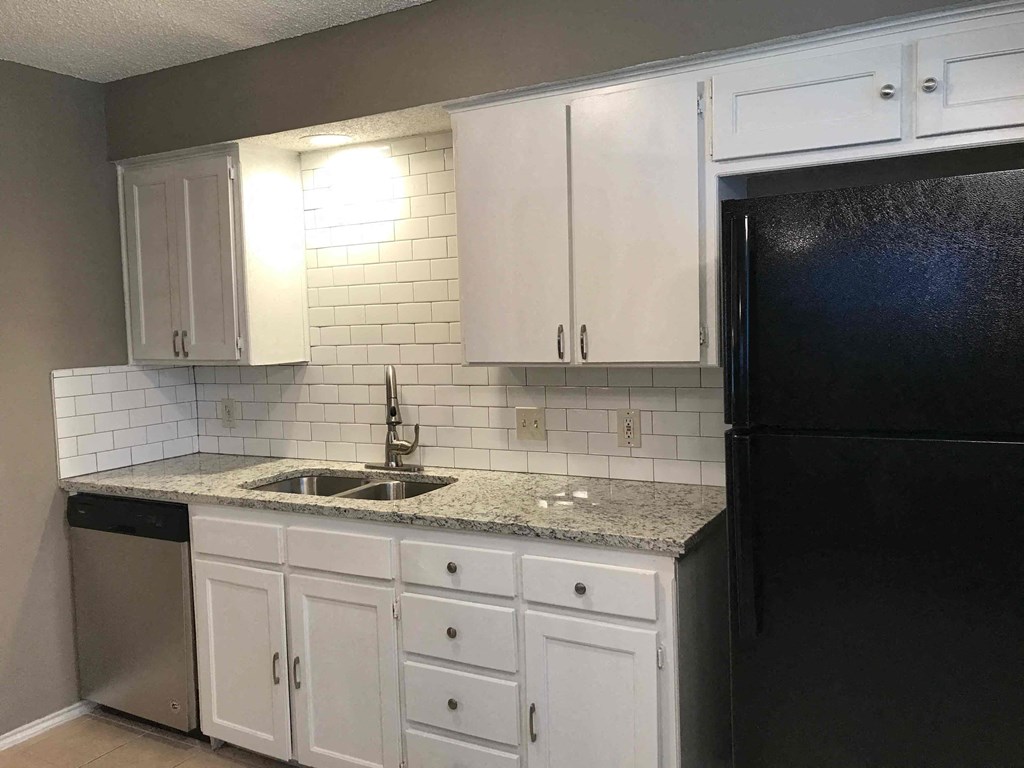 a kitchen with white cabinets and a black refrigerator