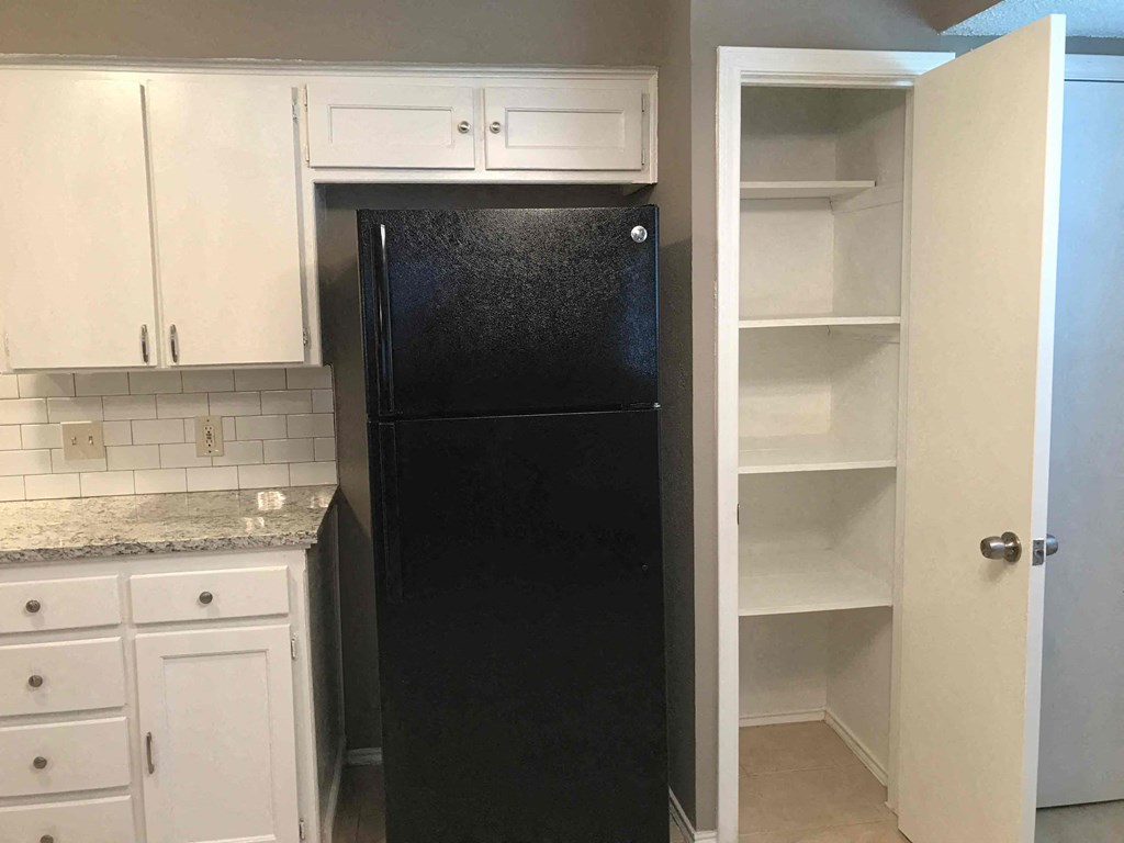 a black refrigerator in a kitchen with white cabinets