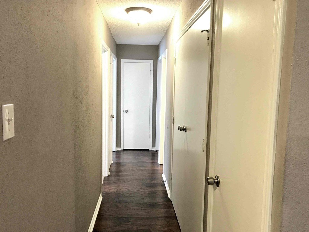 a hallway with white doors and a dark wood floor