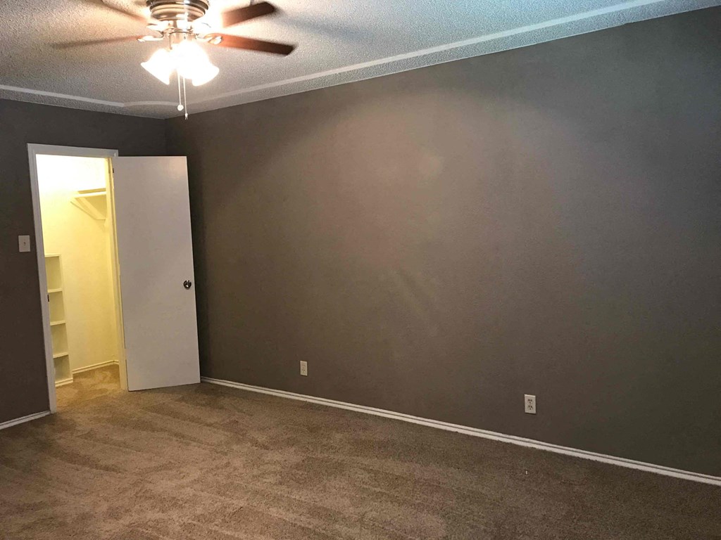 a empty living room with a brown wall and a ceiling fan
